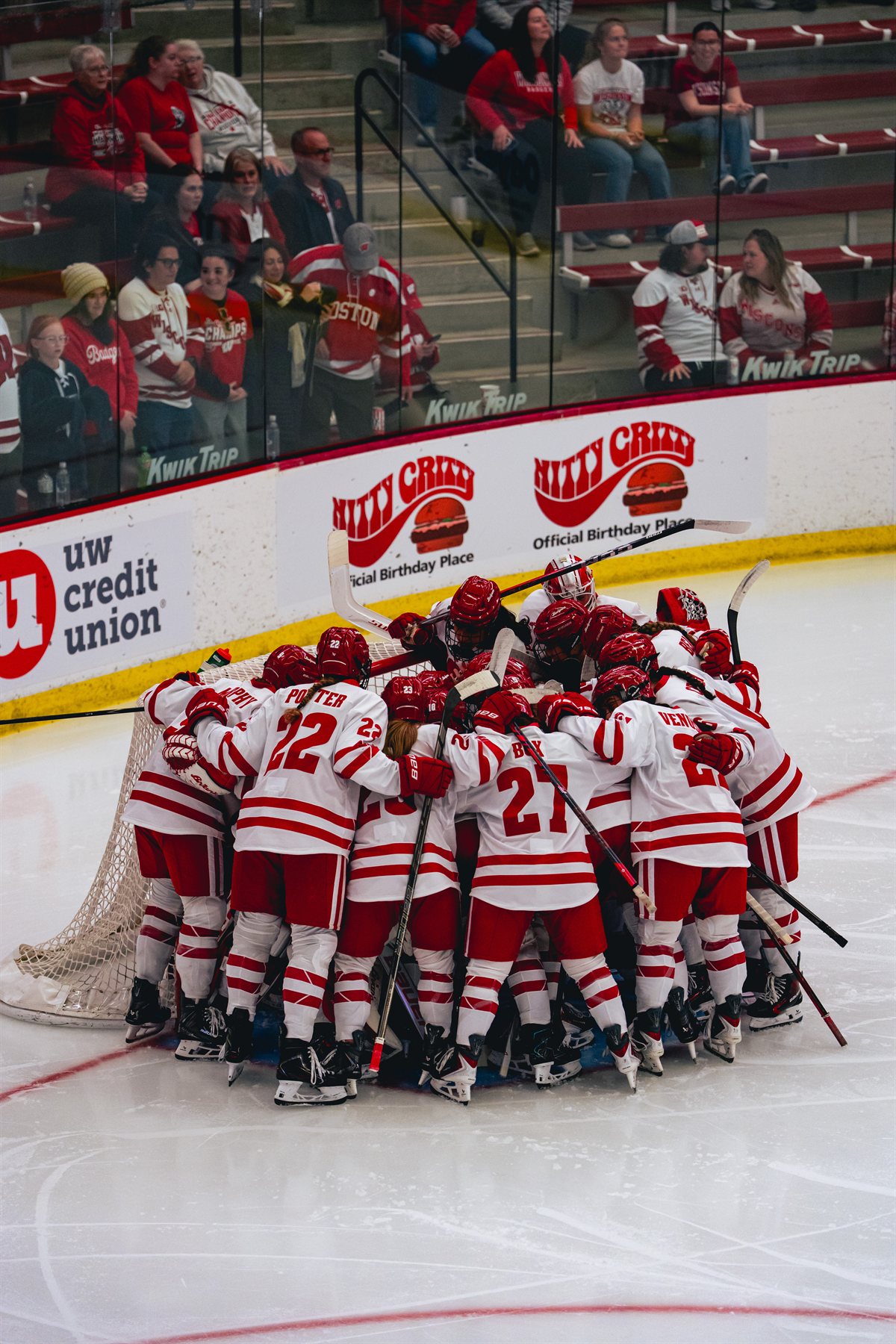 Wisconsin women's hockey team huddling around the goal