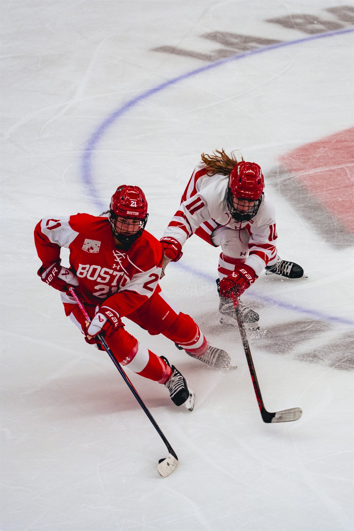 Cassie Hall reaching for the puck alongside a Boston University player