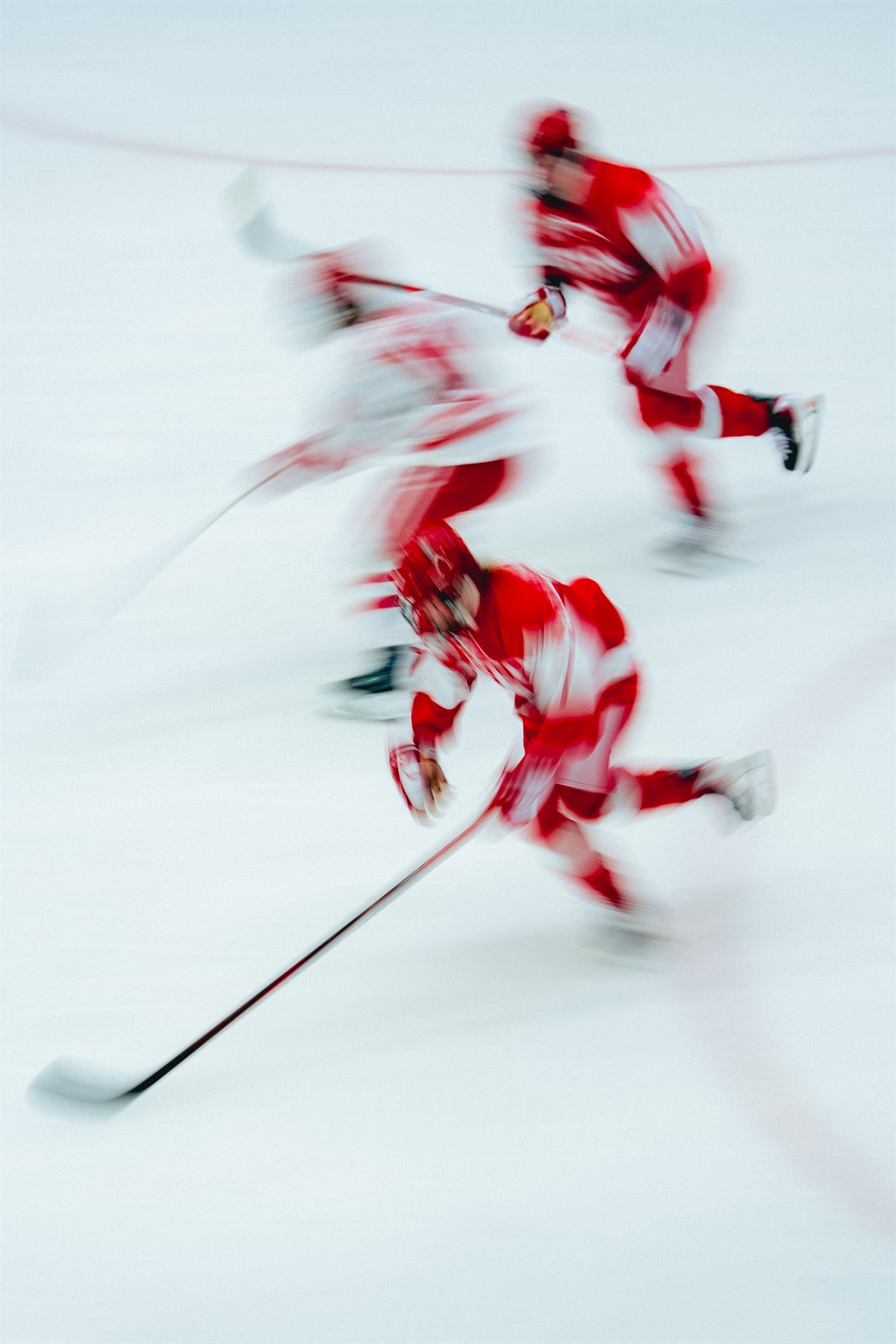 Motion-blurred hockey players racing across the ice with their sticks extended